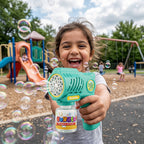 Child holding a 10 Holes Teal Green Bubble Gun with bubbles in a playground setting