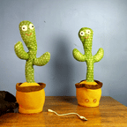 Cactus is Dancing & Talking with smiling cactus design, music icons on the pot and USB charging cable on a wooden table.
